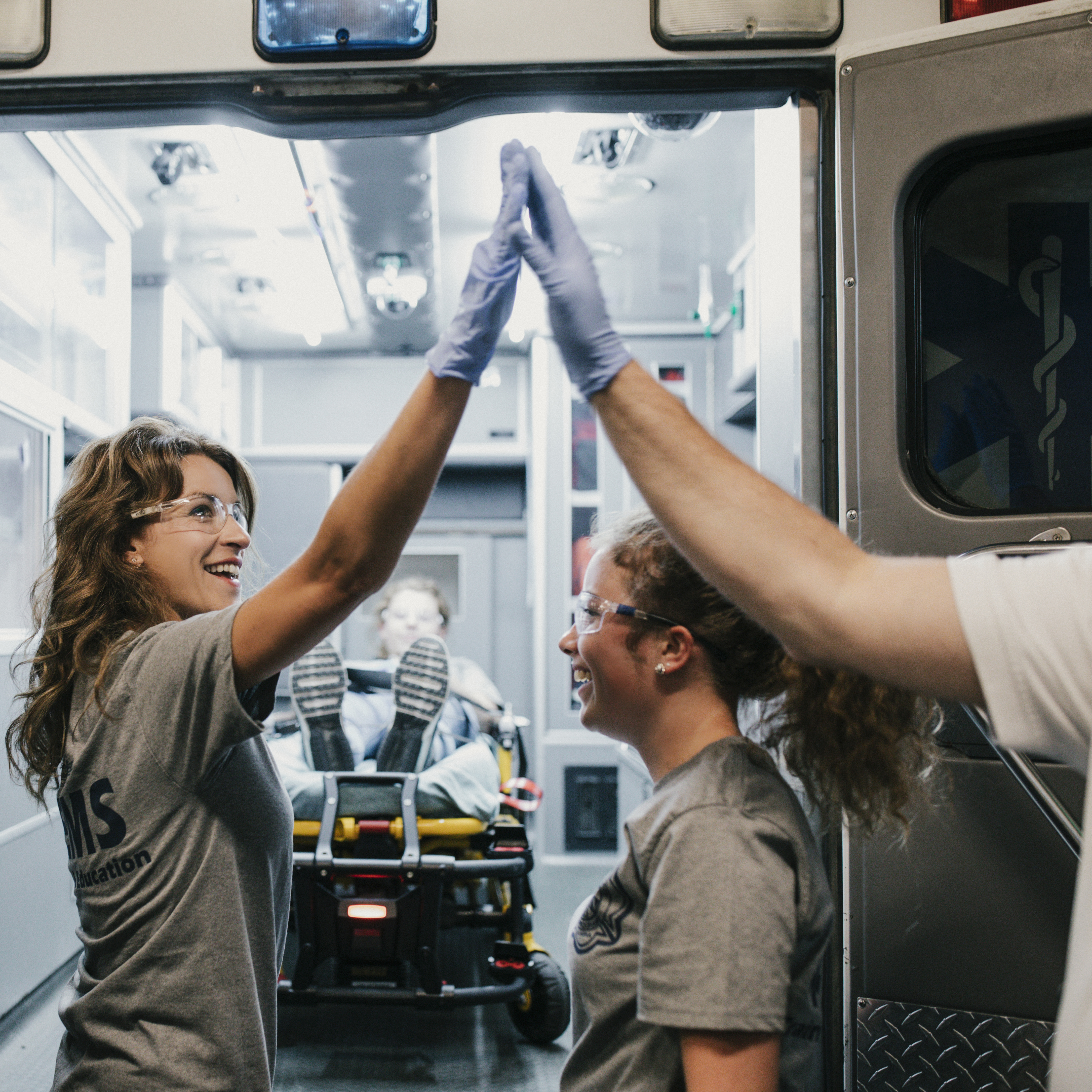 Paramedics student giving a professor a high-five in front of an ambulence.