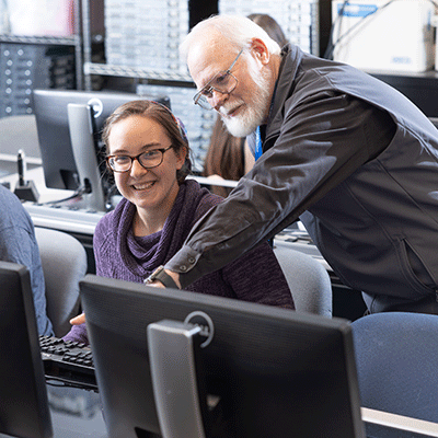 Student with professor in computer classroom.