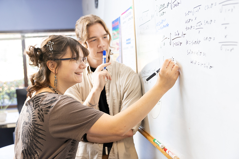 Student smiling with tutor at white board